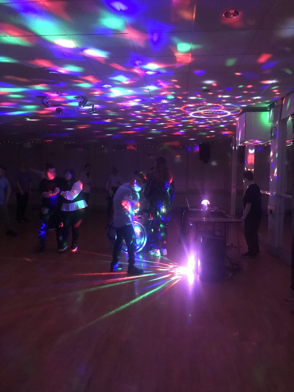 Young people enjoying music and colourful lights at a social event